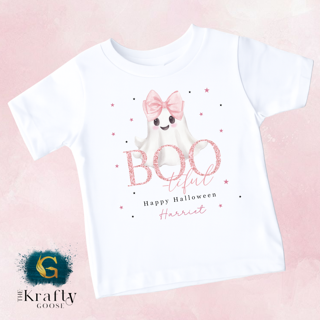 A white t-shirt with a graphic design featuring a ghost character with a bow and the text "Boo! Teful Happy Halloween Harriet" printed on it.