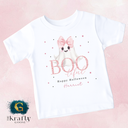 A white t-shirt with a graphic design featuring a ghost character with a bow and the text "Boo! Teful Happy Halloween Harriet" printed on it.