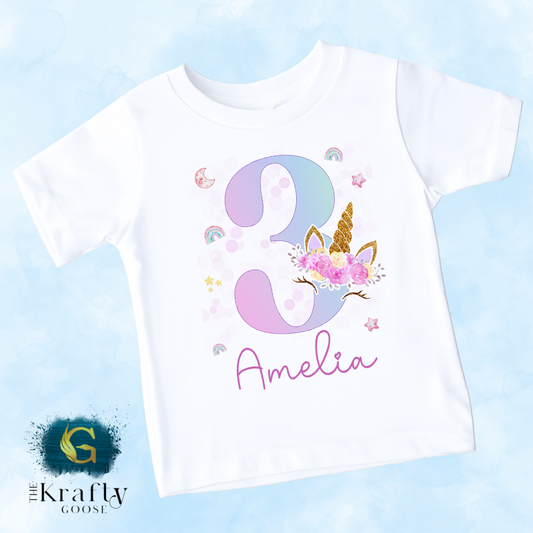 A white t-shirt with a unicorn and the number 3 printed on it, along with the name "Amelia" written below.