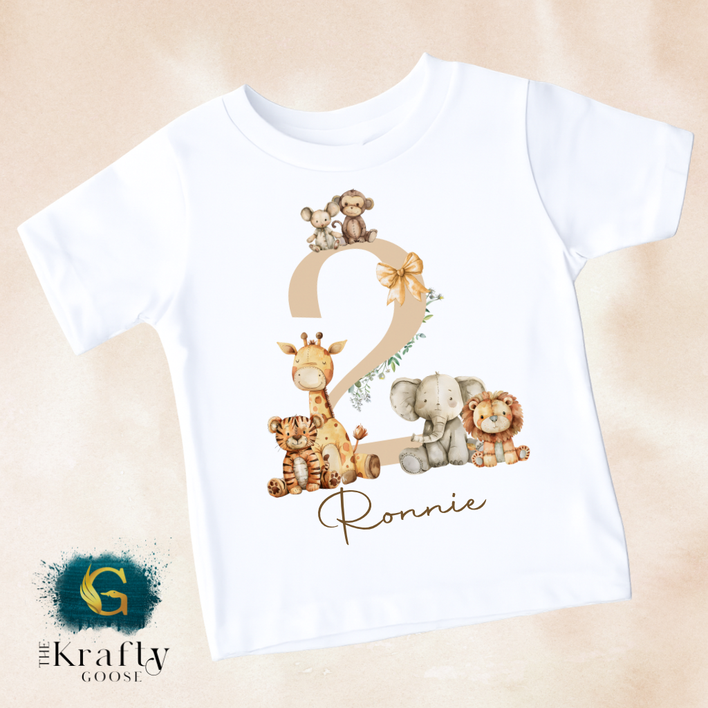 A white t-shirt with a graphic design featuring a number 2 and various animal illustrations, including a giraffe, lion, and elephant.