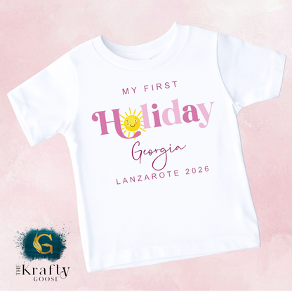 A white t-shirt with text and graphics printed on it, including a sun and the text "My first Holiday Georgia Lanzare 2016".