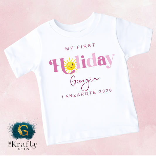 A white t-shirt with text and graphics printed on it, including a sun and the text "My first Holiday Georgia Lanzare 2016".