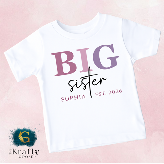A white t-shirt with the text "BIG sister" printed on it, along with the text "SOPHIA EST. 2026" below it.