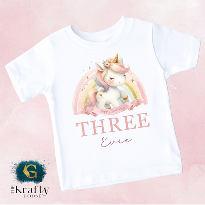 A white t-shirt with a printed design of a unicorn and the text "Happy Birthday Evie" printed on it.