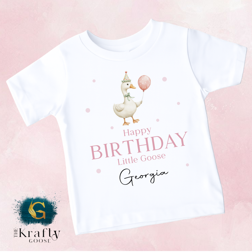 A white t-shirt with a cartoon image of a duck holding a balloon and the text "Happy Birthday Little Goose Georgia" printed on it.