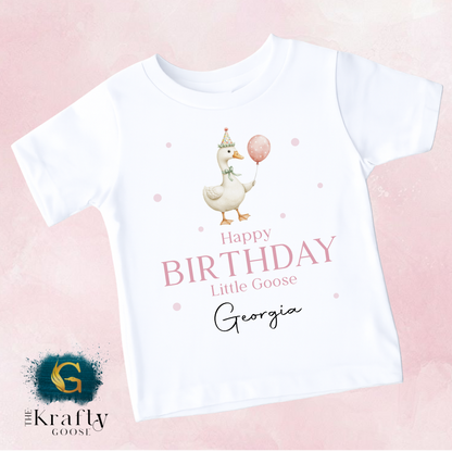 A white t-shirt with a cartoon image of a duck holding a balloon and the text "Happy Birthday Little Goose Georgia" printed on it.