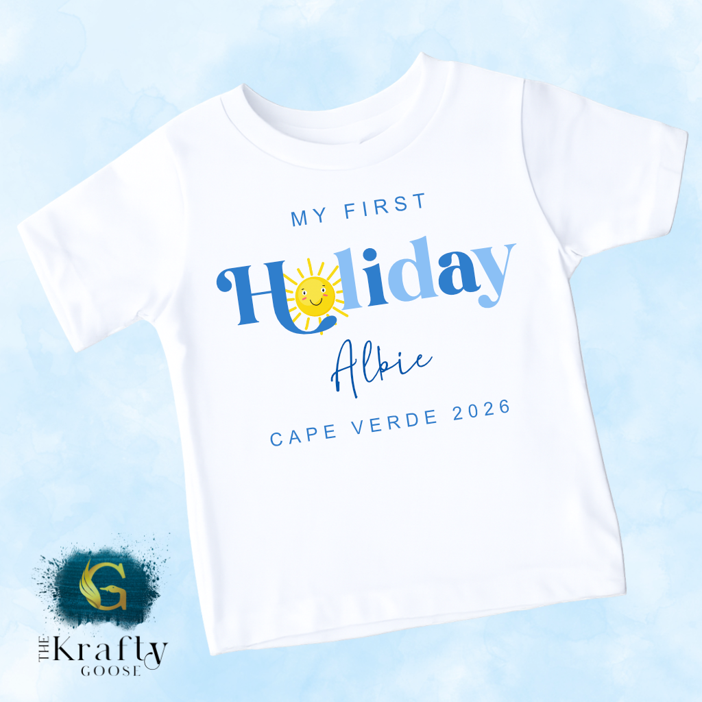 A white t-shirt with text and graphics printed on it, including a sun and the text "My first Holiday Albie Cape Verde 2026".
