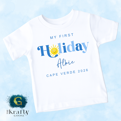 A white t-shirt with text and graphics printed on it, including a sun and the text "My first Holiday Albie Cape Verde 2026".