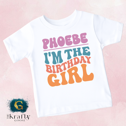A white t-shirt with the text "PHOEBE I'M THE BIRTHDAY GIRL" printed on it.